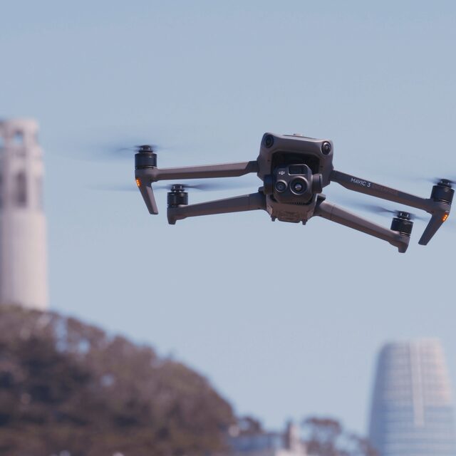 Image of department drone hovering in the air with city in the background