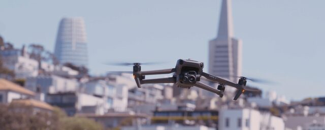 Image of department drone hovering in the air with city skyline in the background